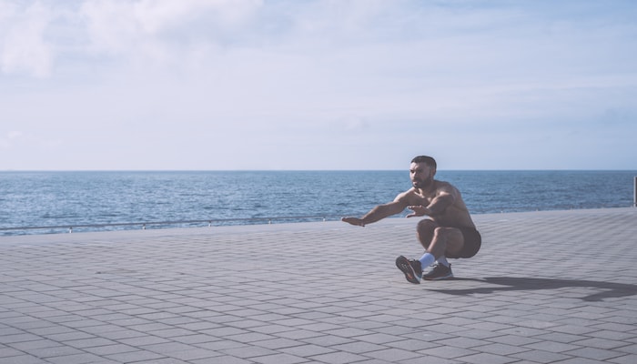 Man doing pistol squats at the beach | DNAfit Blog
