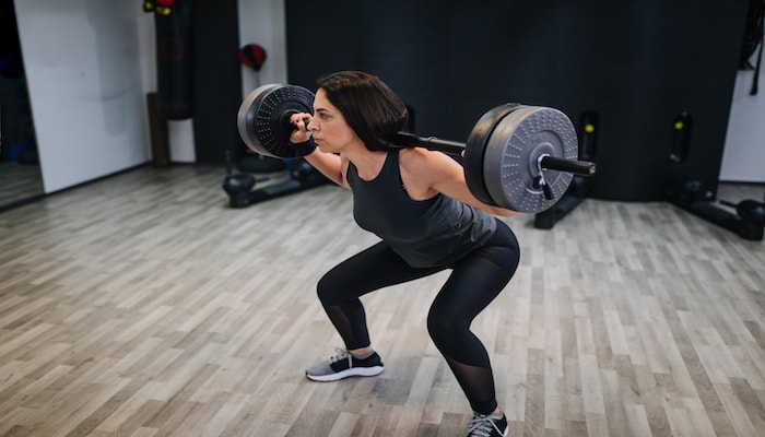 Woman doing weighted squats at the gym | DNAfit Blog