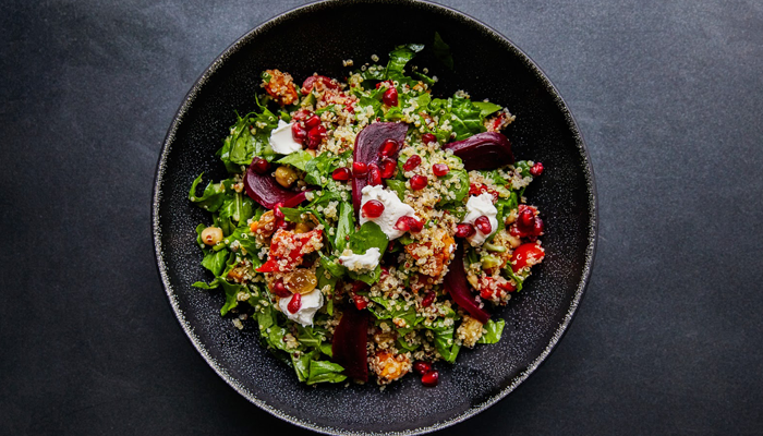 Salad lunch bowl of greens beetroot sesame seeds tomato and feta cheese with pomegranate